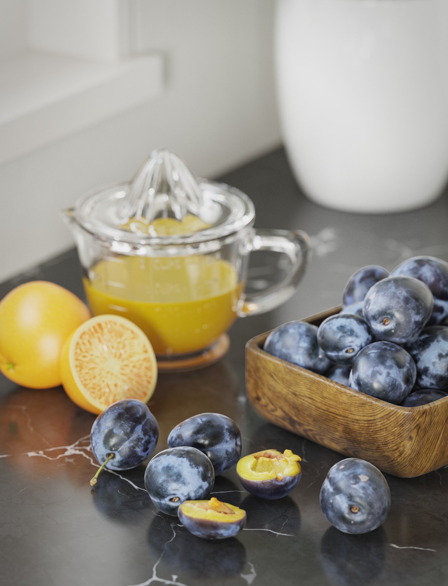 Plums, lemons and a glass juicer on a dark counter